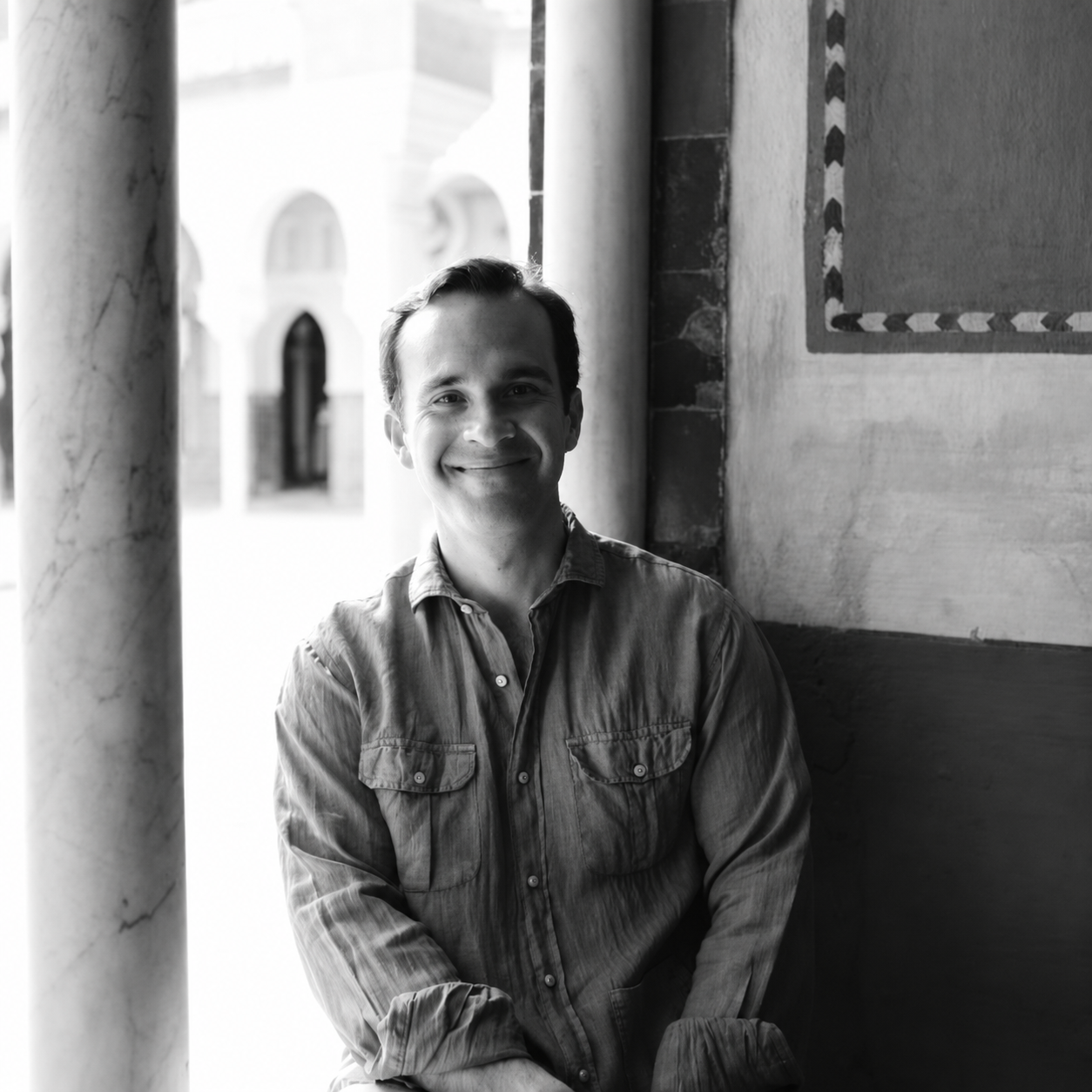 Casto Domínguez sonriendo junto a una columna, en un retrato en blanco y negro